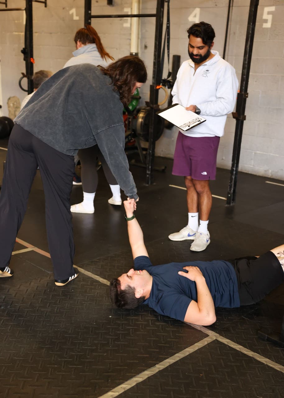 A CrossFit Beyond coach assisting a member during a training session